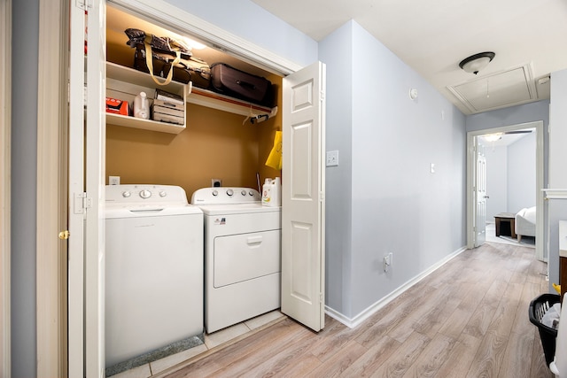 clothes washing area featuring laundry area, attic access, baseboards, light wood-type flooring, and washing machine and dryer