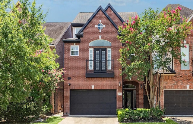 tudor house featuring a garage, concrete driveway, and brick siding