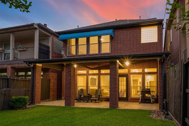 rear view of property featuring a patio area, a yard, brick siding, and fence