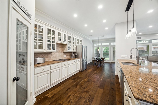 kitchen featuring stone countertops, white cabinets, appliances with stainless steel finishes, glass insert cabinets, and a sink