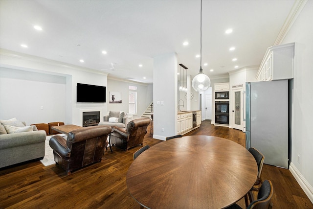 dining room with crown molding, stairs, dark wood-style flooring, and a glass covered fireplace