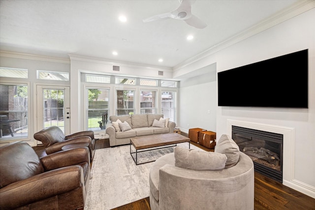 living area with dark wood-type flooring, a glass covered fireplace, and crown molding