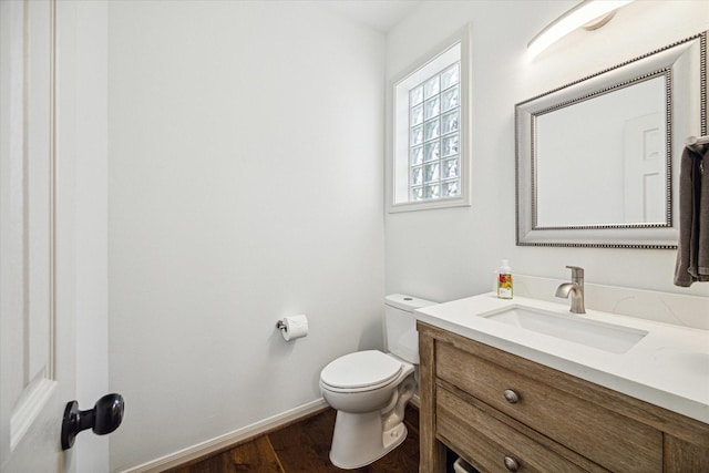 bathroom with baseboards, vanity, toilet, and wood finished floors