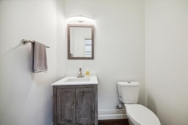 bathroom featuring toilet, baseboards, and vanity