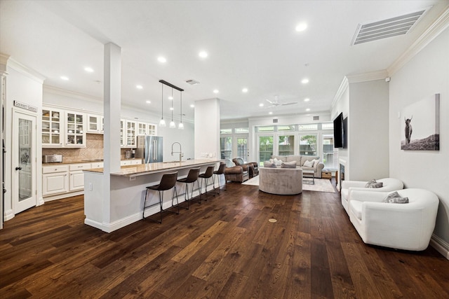 kitchen featuring visible vents, glass insert cabinets, open floor plan, a peninsula, and white cabinetry