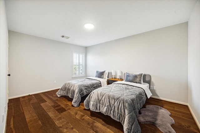 bedroom with dark wood-style floors, visible vents, and baseboards