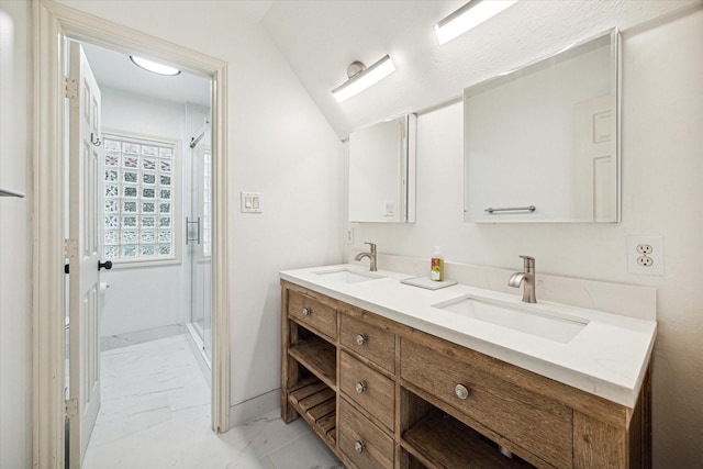 full bathroom with double vanity, marble finish floor, a shower stall, and a sink