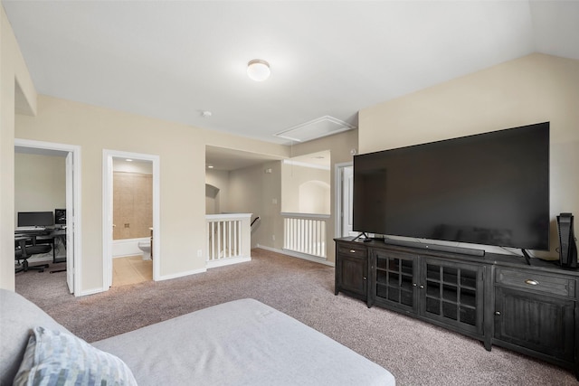 bedroom featuring light colored carpet, baseboards, vaulted ceiling, ensuite bath, and attic access