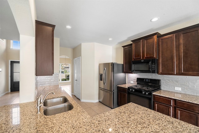 kitchen featuring backsplash, light tile patterned flooring, a sink, light stone countertops, and black appliances