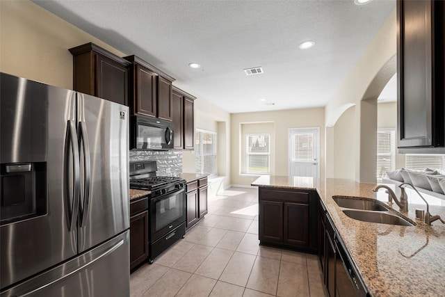 kitchen with light stone counters, light tile patterned floors, visible vents, a sink, and black appliances