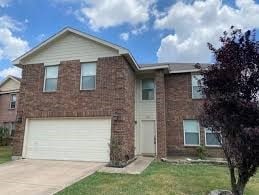 view of front of home with a front yard, brick siding, driveway, and an attached garage