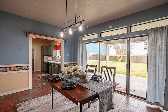 dining room featuring a textured ceiling, stone tile flooring, and baseboards