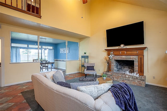 living room with a brick fireplace, a towering ceiling, and baseboards