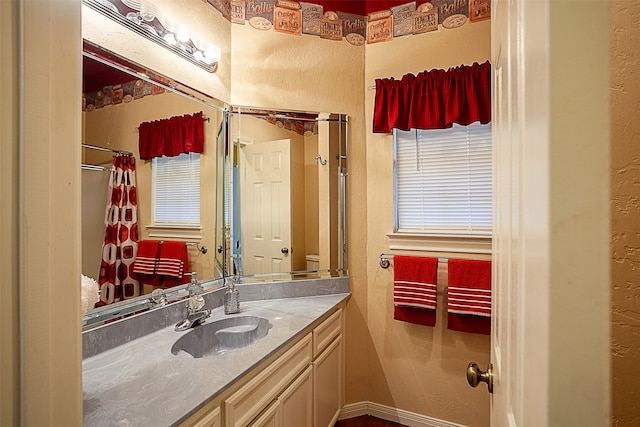 bathroom featuring a textured wall, baseboards, and vanity