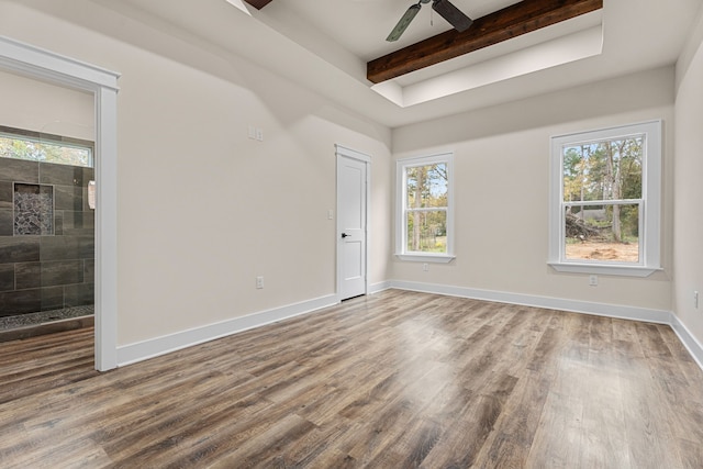 empty room featuring beamed ceiling, wood finished floors, a ceiling fan, and baseboards