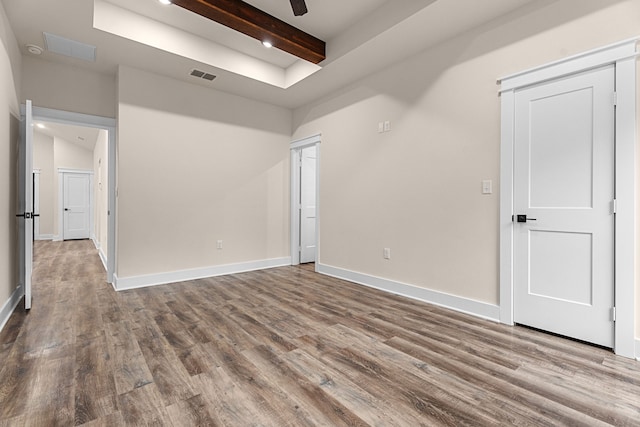 empty room with ceiling fan, beamed ceiling, wood finished floors, and baseboards