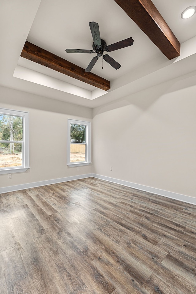 unfurnished room with ceiling fan, beamed ceiling, wood finished floors, and baseboards