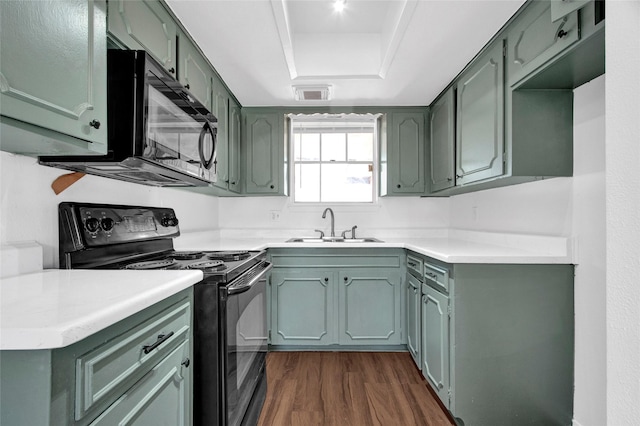 kitchen featuring dark wood-style floors, light countertops, visible vents, a sink, and black appliances