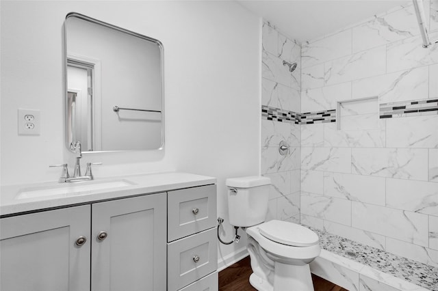 full bathroom with a stall shower, baseboards, toilet, wood finished floors, and vanity