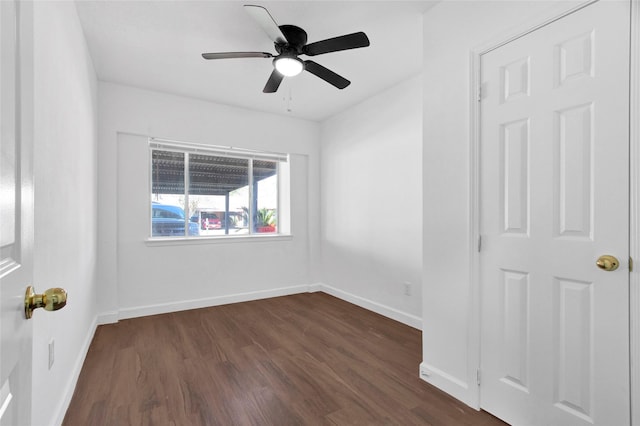 unfurnished room with dark wood-style flooring, a ceiling fan, and baseboards