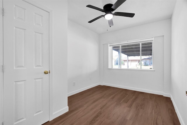 spare room with a ceiling fan, baseboards, and dark wood-type flooring