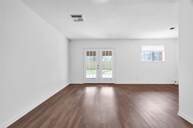 empty room featuring french doors, visible vents, dark wood finished floors, and baseboards