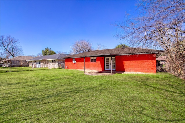 back of house with a yard, brick siding, fence, and french doors