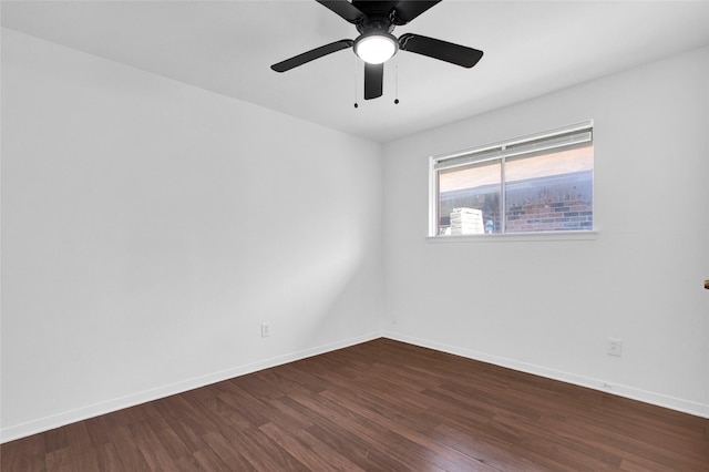 spare room with dark wood-style floors, baseboards, and a ceiling fan