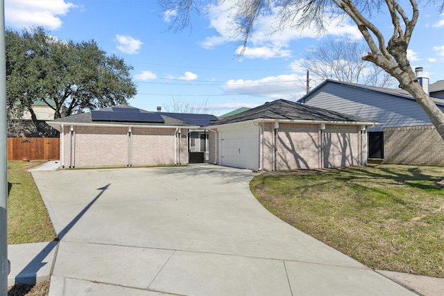 view of front of home featuring driveway, an attached garage, fence, roof mounted solar panels, and a front yard