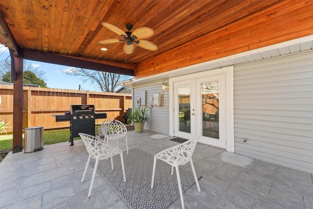 view of patio / terrace featuring ceiling fan, a grill, fence, outdoor dining area, and french doors