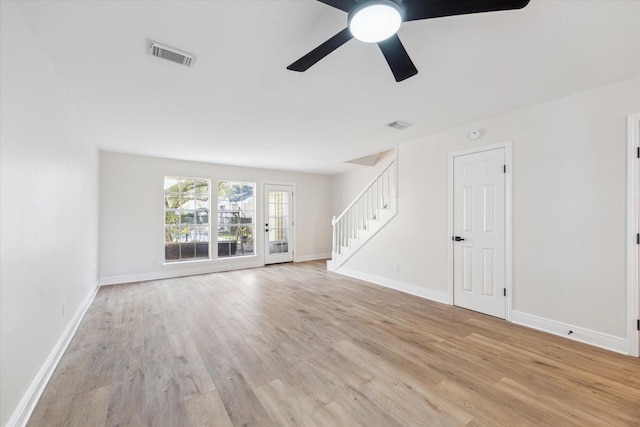 unfurnished living room featuring light wood-style flooring, visible vents, stairway, and baseboards