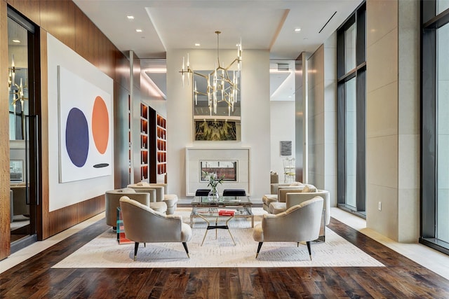 living room with hardwood / wood-style flooring, recessed lighting, a high ceiling, an inviting chandelier, and a fireplace