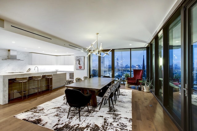 dining space with expansive windows, a view of city, light wood-style floors, and a notable chandelier