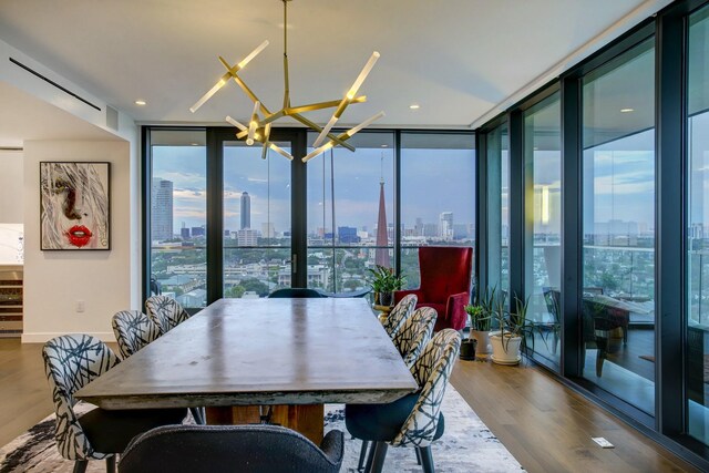 dining area with baseboards, a chandelier, floor to ceiling windows, wood finished floors, and a view of city