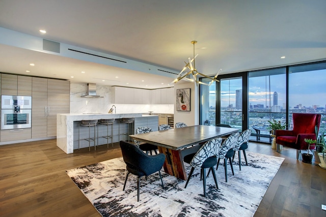 dining area with wood finished floors, recessed lighting, expansive windows, a city view, and a notable chandelier