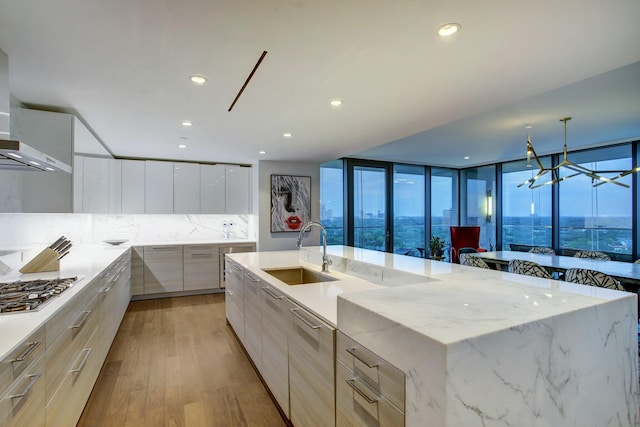 kitchen with tasteful backsplash, stainless steel gas cooktop, light wood-style floors, modern cabinets, and a sink