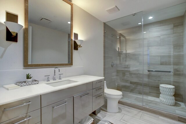 bathroom with vanity, toilet, visible vents, and a stall shower