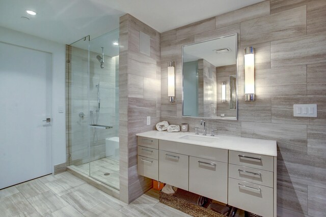 full bathroom with tile walls, a stall shower, and vanity