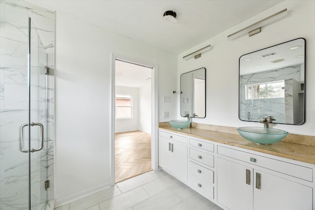 bathroom featuring double vanity, a marble finish shower, and a sink