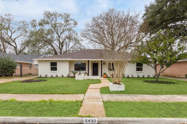 ranch-style home featuring brick siding, fence, a porch, and a front yard