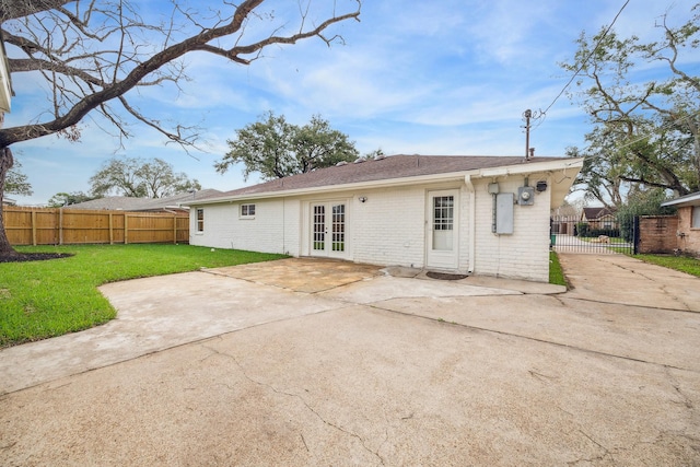 rear view of property featuring french doors, brick siding, a yard, a patio area, and fence