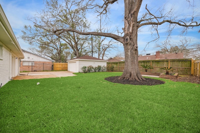 view of yard featuring a garage, a patio area, a fenced backyard, and an outbuilding