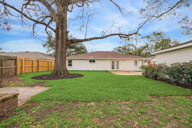 rear view of property featuring french doors, a fenced backyard, a yard, and a patio