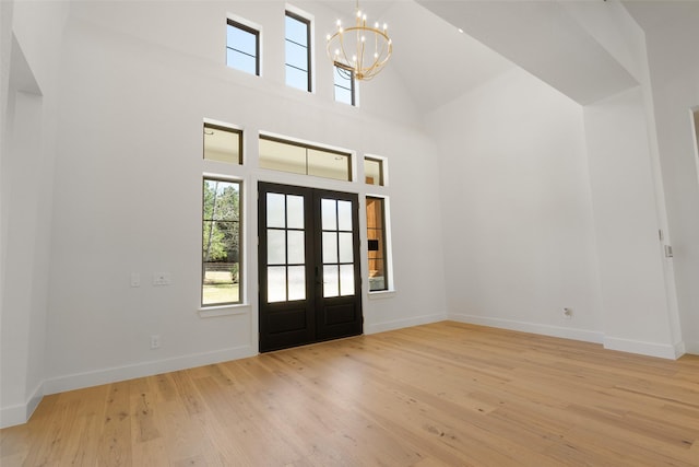 entryway featuring a high ceiling, wood finished floors, baseboards, french doors, and an inviting chandelier