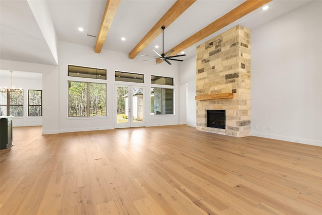 unfurnished living room with beam ceiling, french doors, a fireplace, light wood finished floors, and baseboards