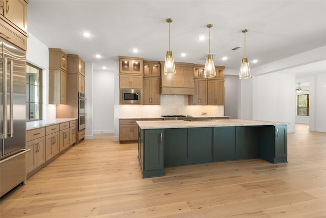 kitchen with built in appliances, a spacious island, visible vents, light wood-style floors, and tasteful backsplash