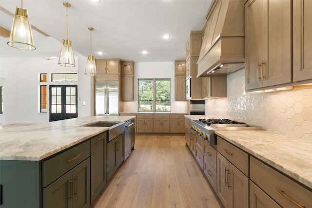 kitchen featuring built in appliances, light wood-style floors, french doors, tasteful backsplash, and custom range hood