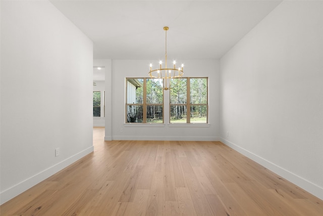 unfurnished dining area featuring baseboards, light wood-type flooring, and a notable chandelier