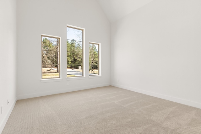 spare room with light carpet, baseboards, and high vaulted ceiling