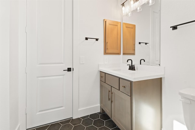 bathroom with tile patterned flooring, baseboards, vanity, and toilet